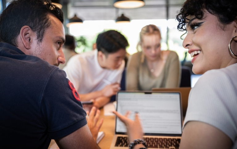 Two students discussing in front of a computer.