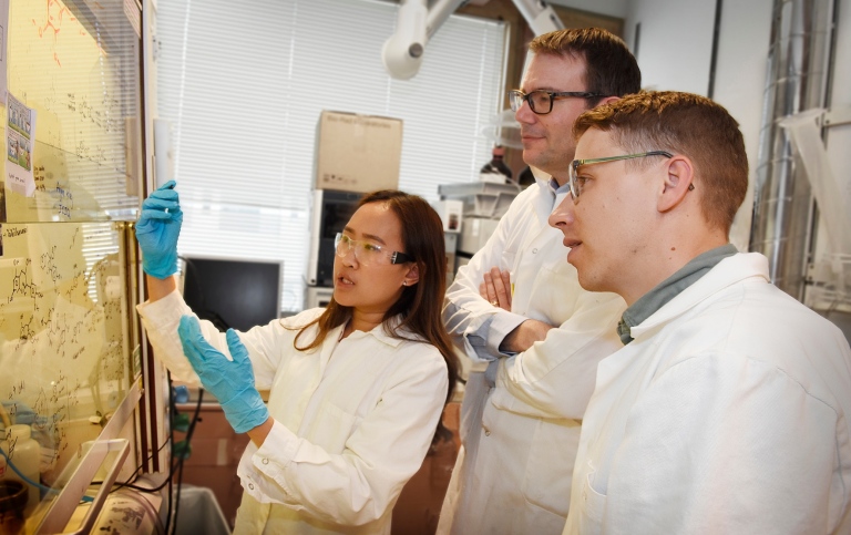 Three researchers in the lab looking at a whiteboard.