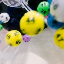 A close-up of colorful lottery balls bouncing inside a lottery machine during a draw.